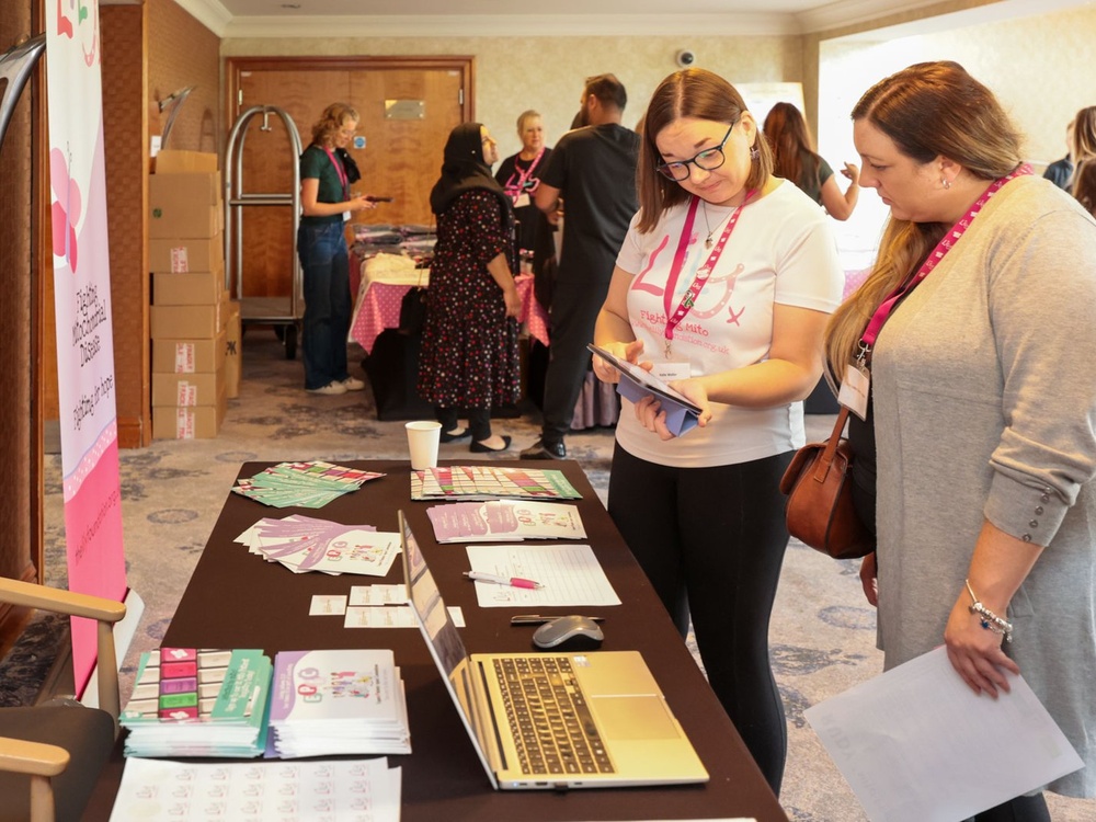 A lady in a Lily t-shirt holds a leaflet open looking at it while another lady stands at her side and looks over her shoulder