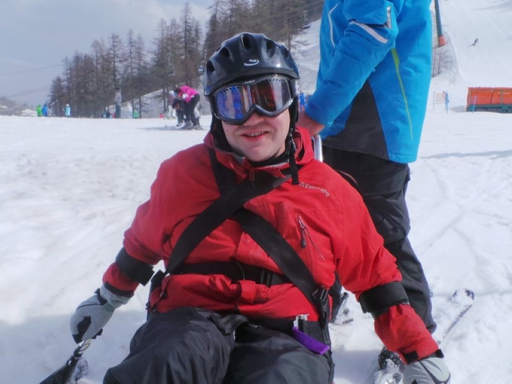 A man on sit-down skis being pushed across the snow