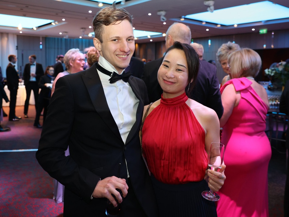 A man and lady with their arms around each other holding a glass of fizz wearing party clothes