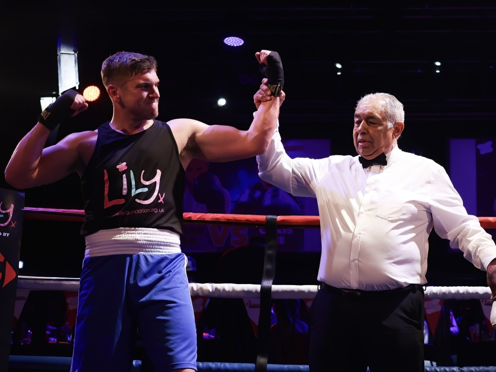 A winning boxer raises his arms with the ref in the ring at the Clapham Grand