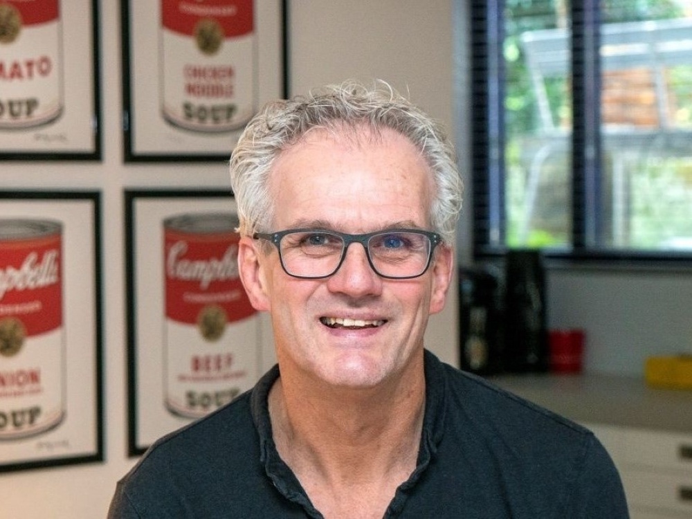A man with white hair and glasses smiling at the camera