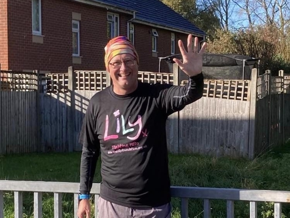 A man in Lily top smiling and waving