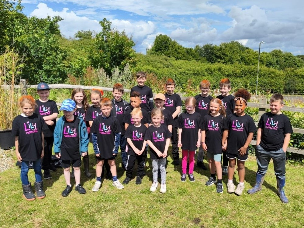 A group of schoolchildren standing together outside wearing Lily Foundation tops