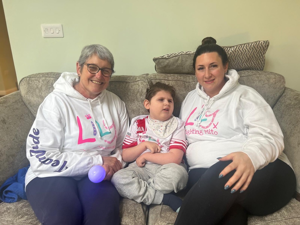 A young mito warrior sitting between his mum and nanna all wearing Lily hoodies