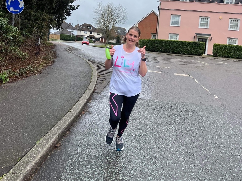 A women running in a Lily Foundation t-shirt with her thumbs up