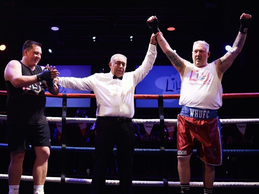 Two boxers either side of the ref in the ring at the Lily Fight NIght