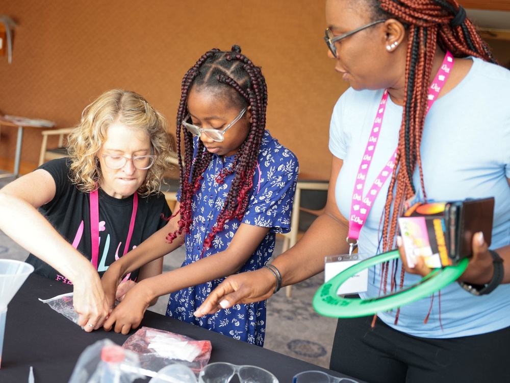 A girl is concentrating on a craft activity on the table in front of her