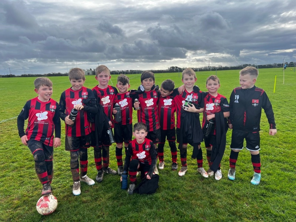 A group of young boys standing in their kit on a football pitch