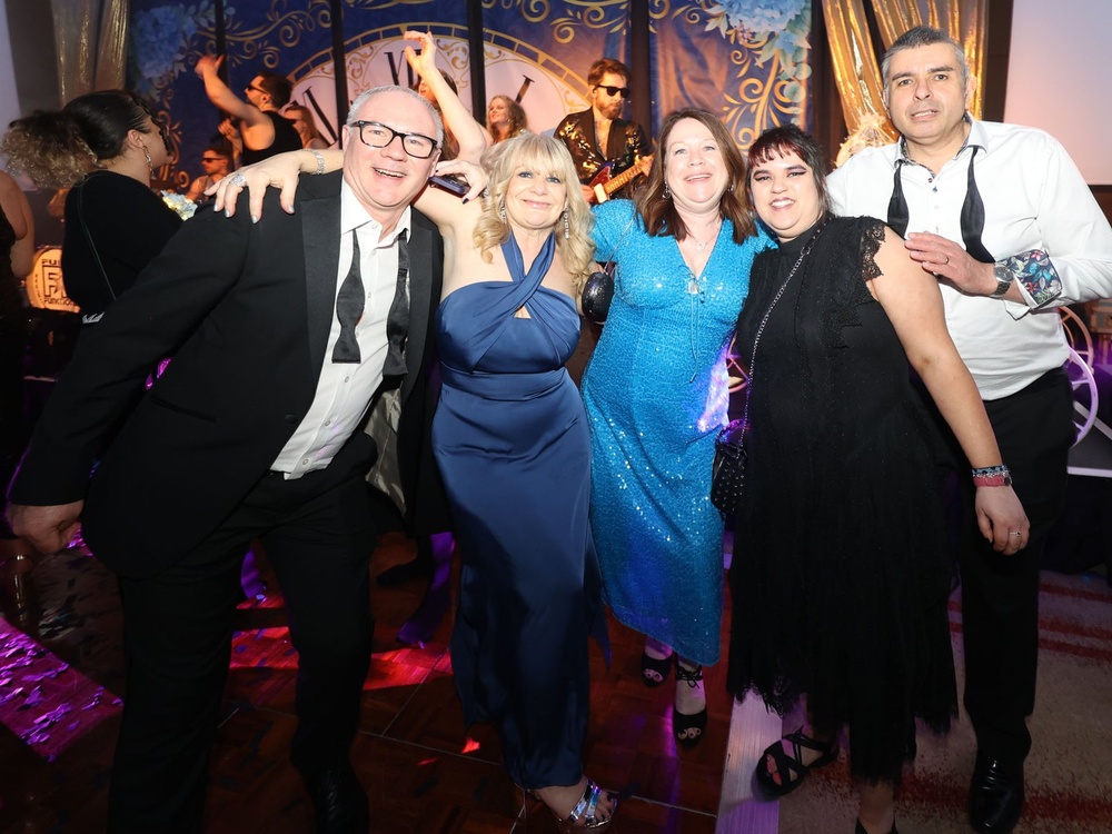 A group of men and ladies with their arms around one another on the dancefloor