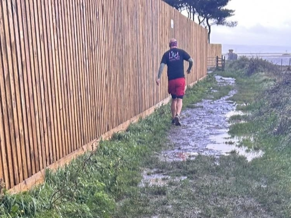 A man in a Lily top running away from the camera through mud