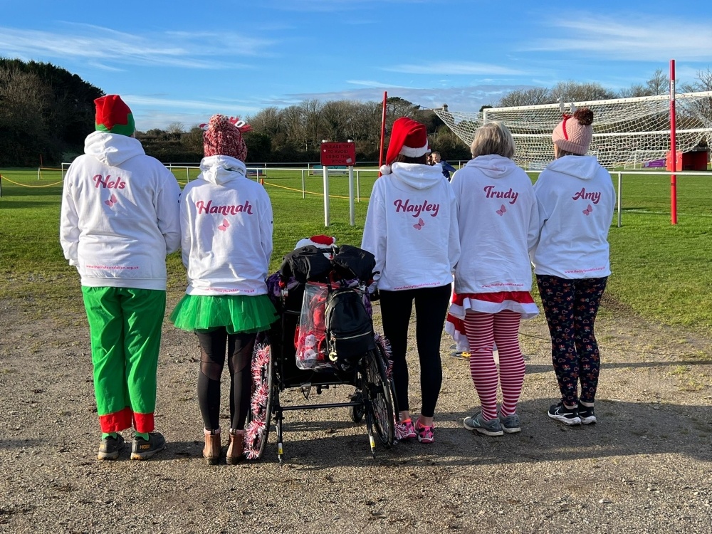 A group of ladies standing showing their backs with their names on their Lily hoodies