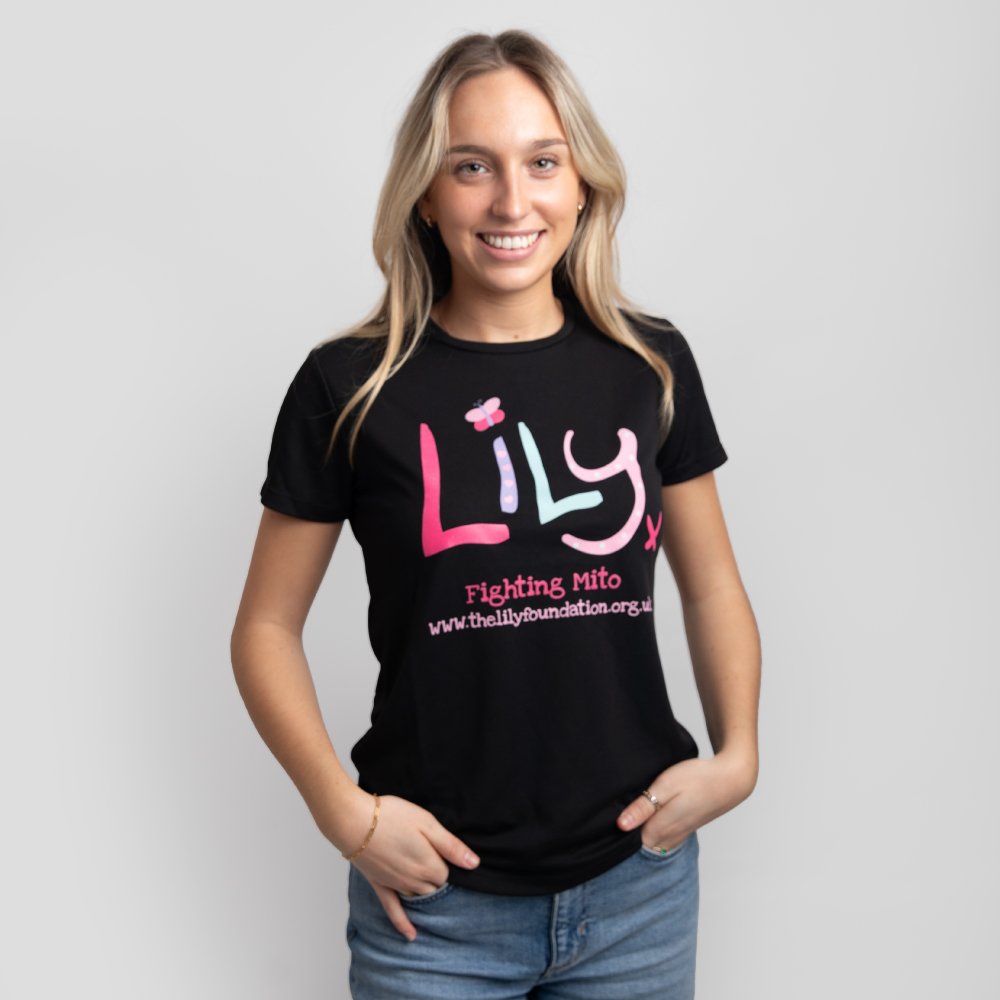 A smiling woman in a black performance top featuring the Lily Foundation logo and fighting mito underneath.