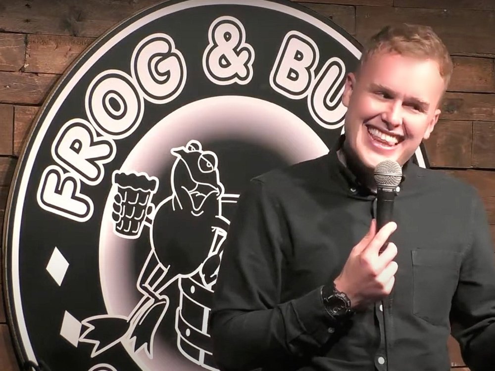 A comedian standing on stage with a mic at the Frog and Bucket Comedy Club Manchester