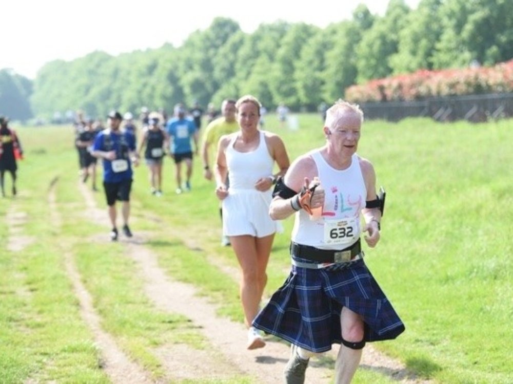 Edinburgh Marathon 2025 - A man in a Lily top and kilt running along a track at the Edinburgh Marathon