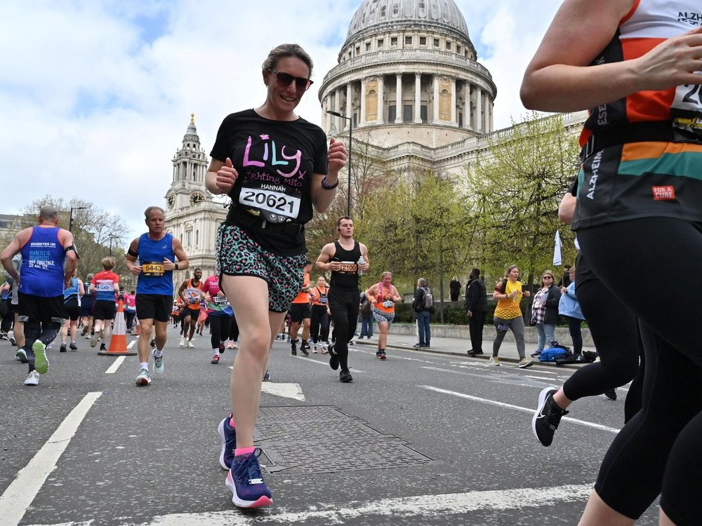 London Landmarks Half Marathon 2025 - A woman in a Lily t-shirt running past St Paul's Cathedral in London