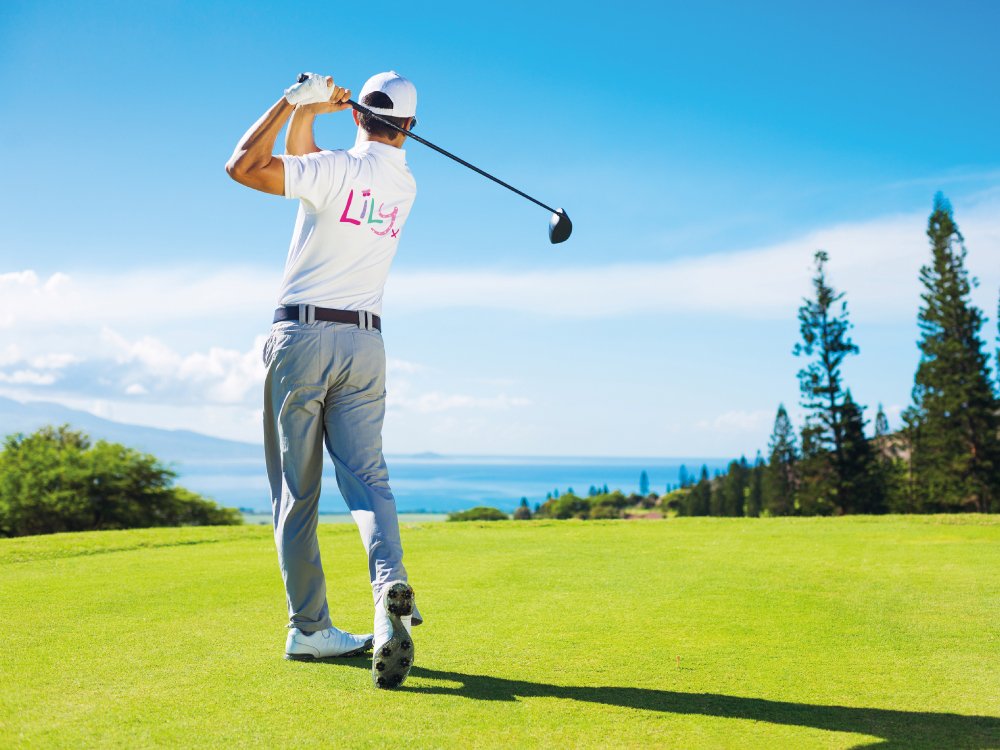 A man on a golf course taking a swing with a club