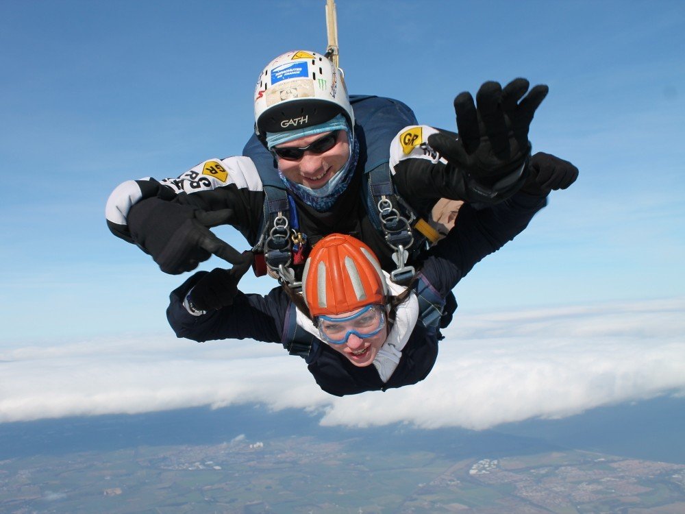 Two people falling through blue sky in a tandem skydive for charity