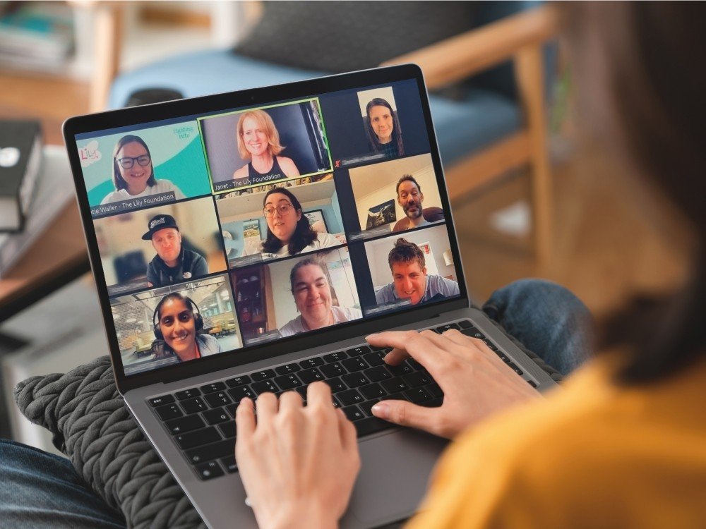 Lady on her laptop with a shot of people in a Zoom room on the screen