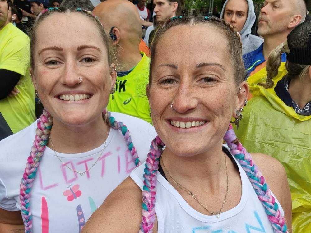 Twins in Lily vests and colourful plaits smiling