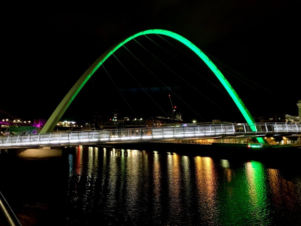 Gateshead Millennium Bridge lit up green in the darkness over the River Tyne