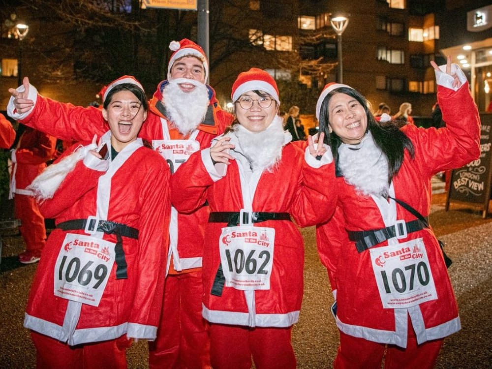 Runners dressed in Santa suits in a city street for a charity event