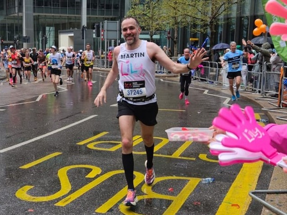 A man in a Lily vest running and waving at spectators