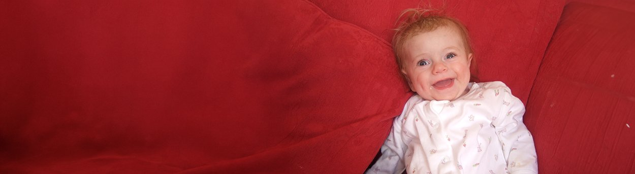 Baby Lily with a big smile on a red blanket