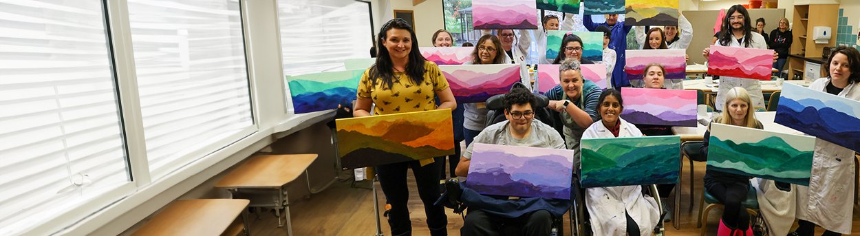 Group of young adult mito patients holding up their colourful paintings of the lake District