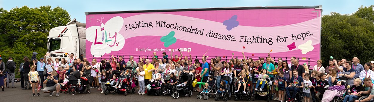 Lots of Lily families, standing in front of a huge lily branded lorry with bright pink sides and butterflies