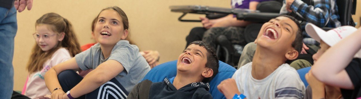 A group of children with mitochondrial disease laughing at the Lily support weekend