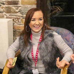 Amy Johnson, young smiling adult with long brown hair and hooped earrings, wearing a furry top