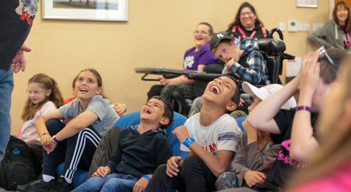 A group of children with mitochondrial disease laughing at the Lily support weekend