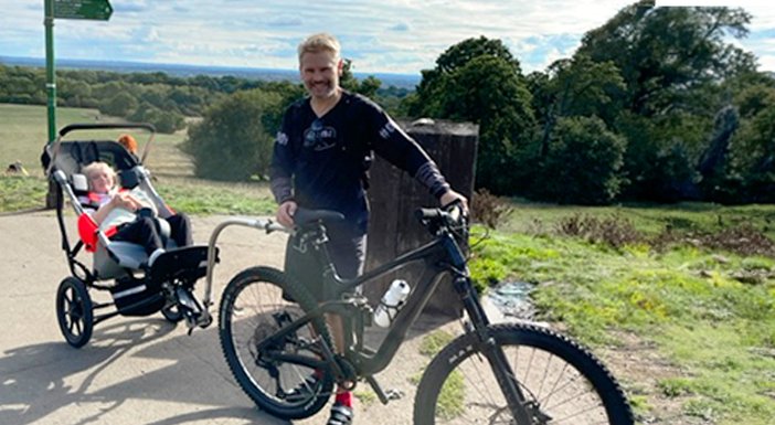 Dad on mountain bike, towing his daughters adjusted wheelchair. stopped at the top of a hill to enjoy the view