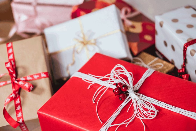 A pile of boxes wrapped in Christmas paper in red white covered in ribbon and bows