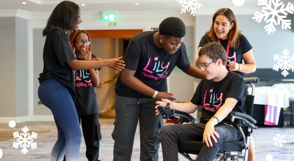 Young mito patient in a wheelchair surrounded by people at the Lily support weekend