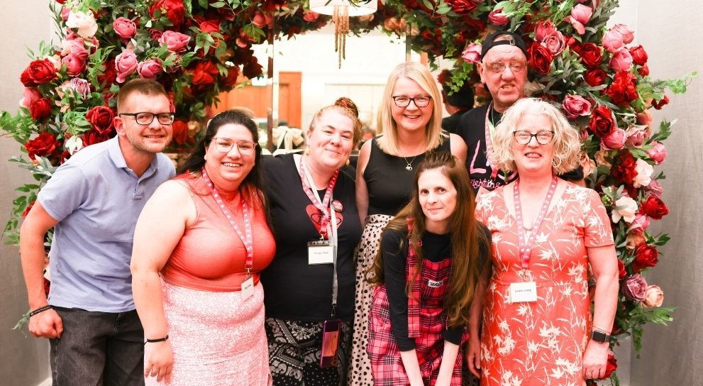 A group of people standing together below a large display of flowers