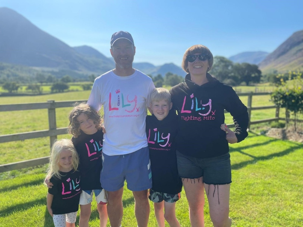 A mum, dad and three children in the Lake District countryside, all wearing Lily Foundation tops