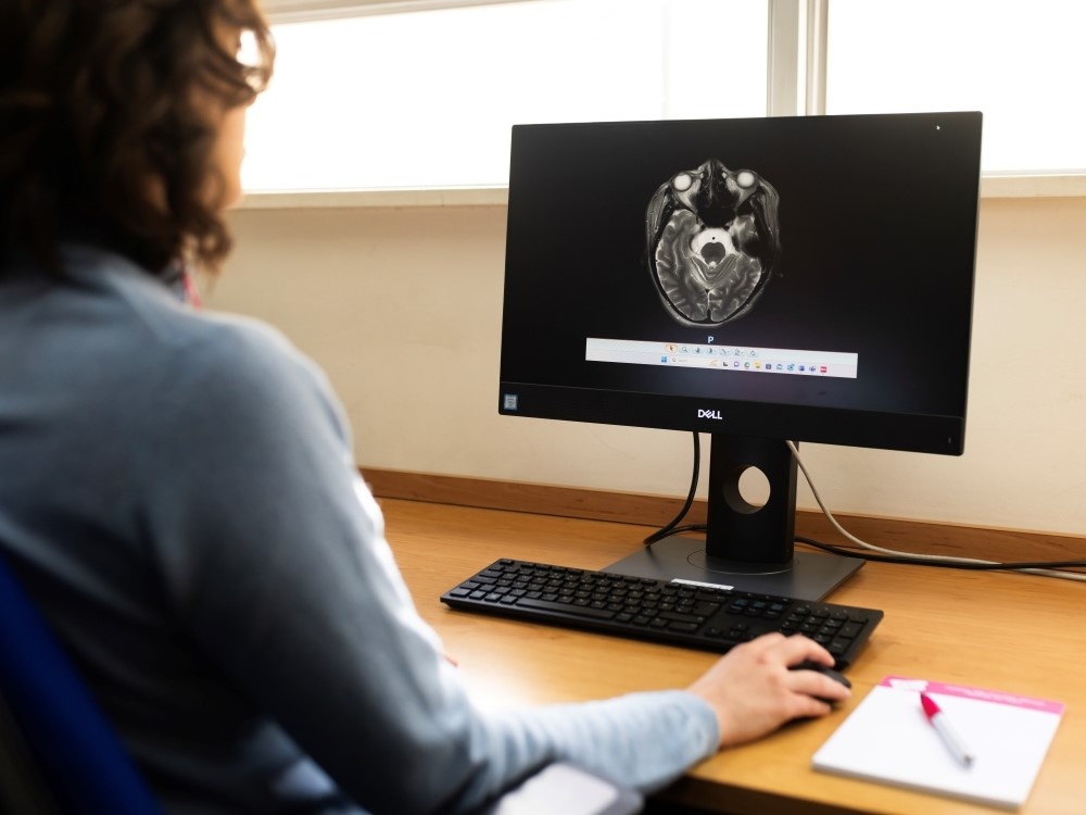 A lady sitting at a desk using a mouse with a screen in front of her