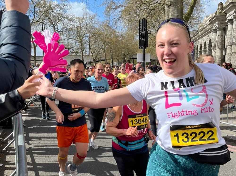 A woman in a white Lily top running and high fiving spectators