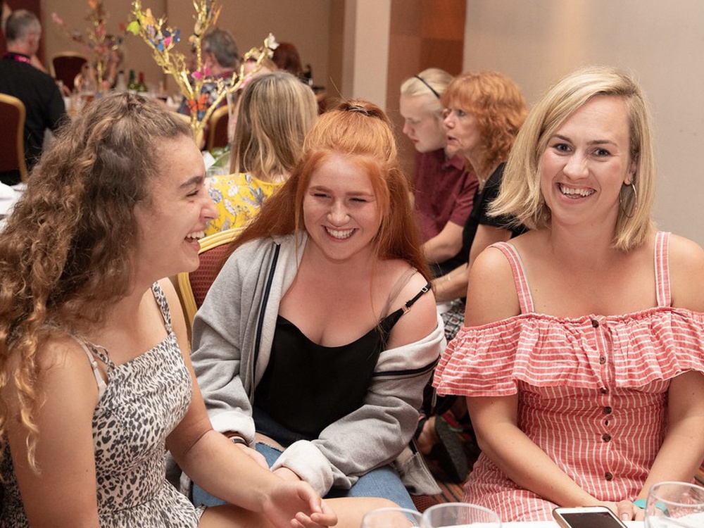 Three women sat around a table with drinks glasses on it