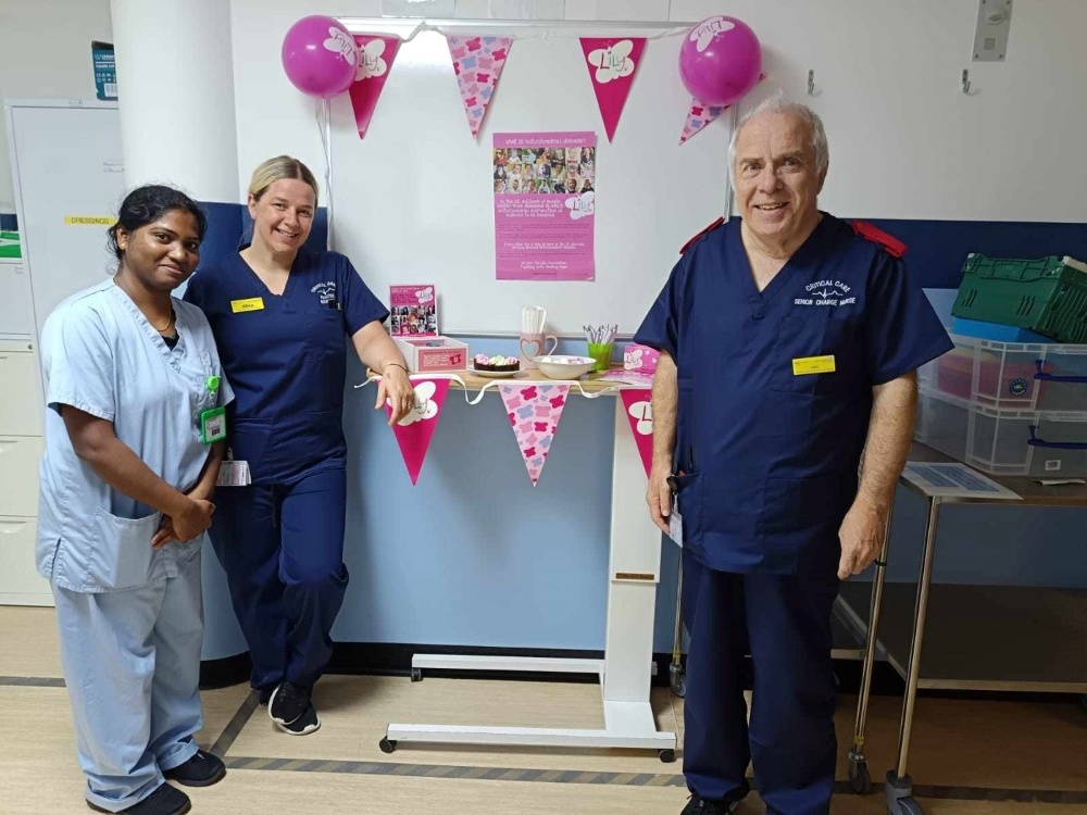 Three people standing around a display of Lily foundation balloons and bunting