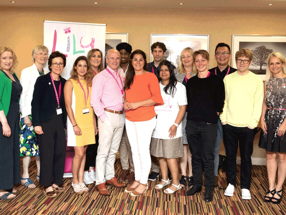 A group of adults stand together smiling at the camera