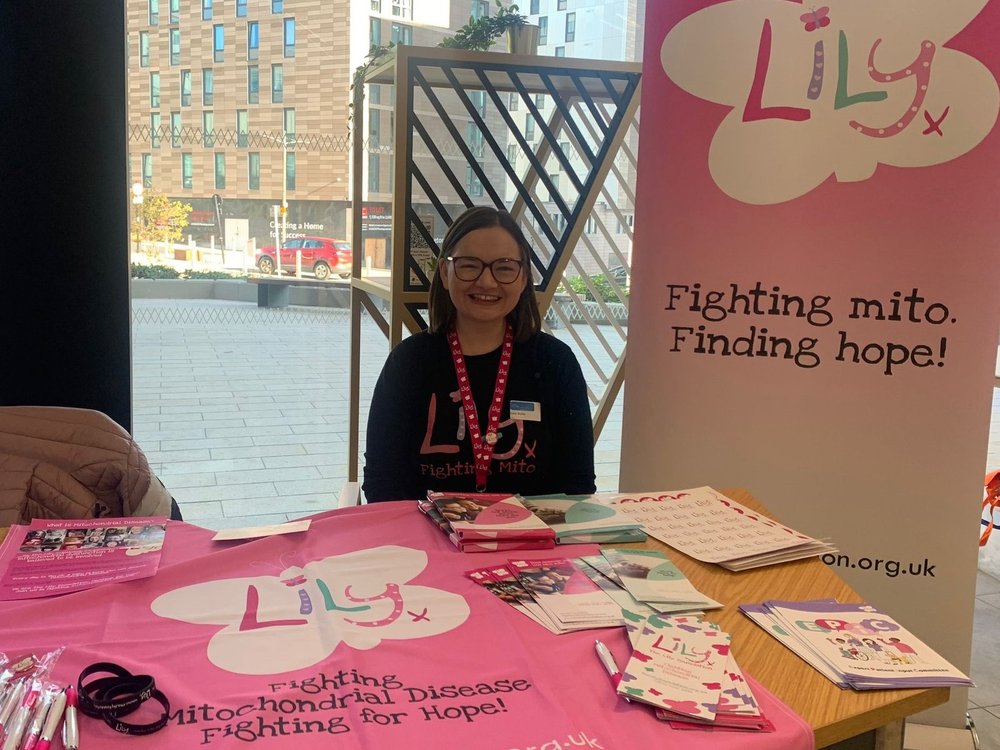 A lady in a Lily-branded t-shirt sitting behind a desk with Lily leaflets