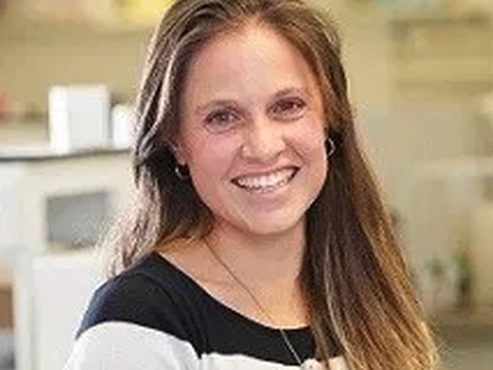 A head shot of a woman with long brown hair smiling at the camera