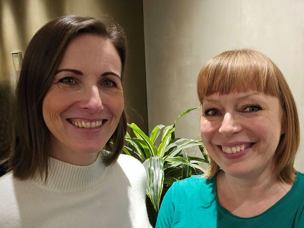 Two ladies standing side by side smiling