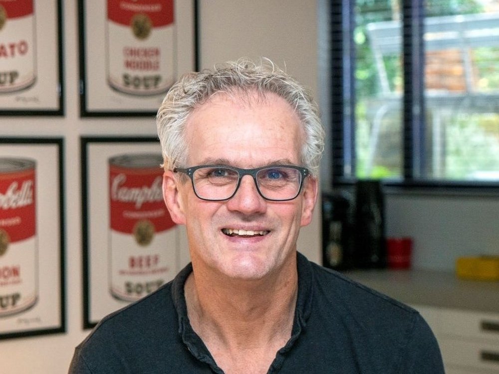 A man with white hair and glasses smiling at the camera