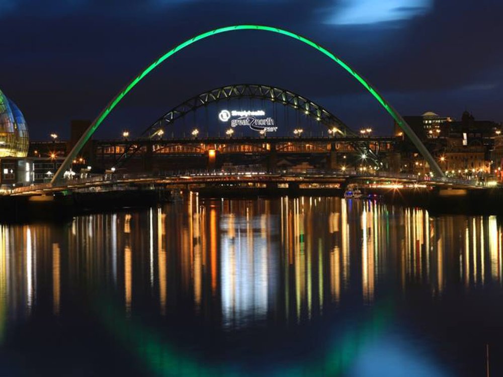 A bridge at night lit up with green lights