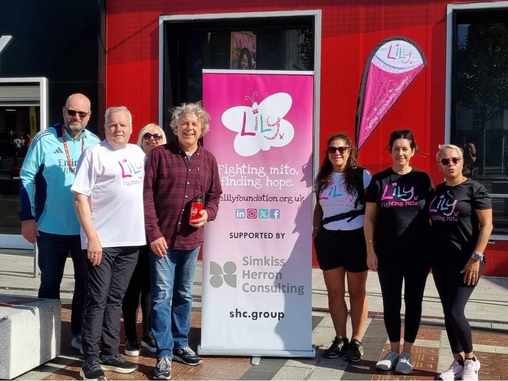 Kevin Day, comedian Alan Davies and supporters standing next to a Lily banner