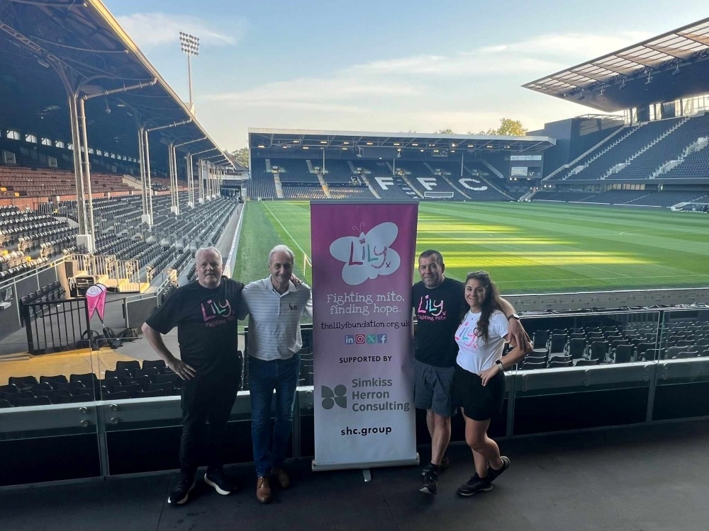 Kevin and team inside Fulham's stadium with a Lily banner