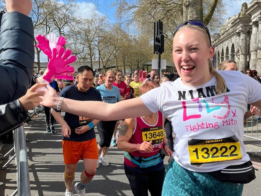 A woman in a white Lily top running and high fiving spectators